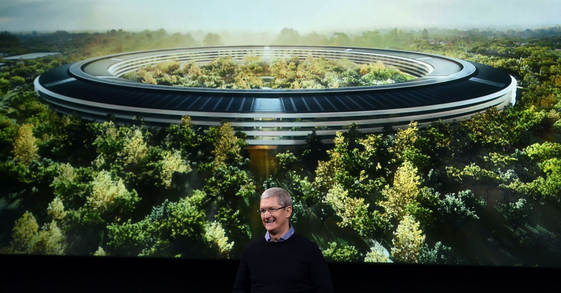 Apple CEO Tim Cook stands in front of a slide of the company's new campus which is under construction during a media event at Apple headquarters in Cupertino, California