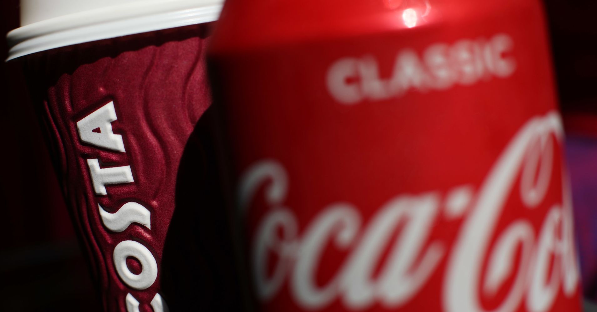 A can of Coca-Cola next to a cup of Costa coffee.