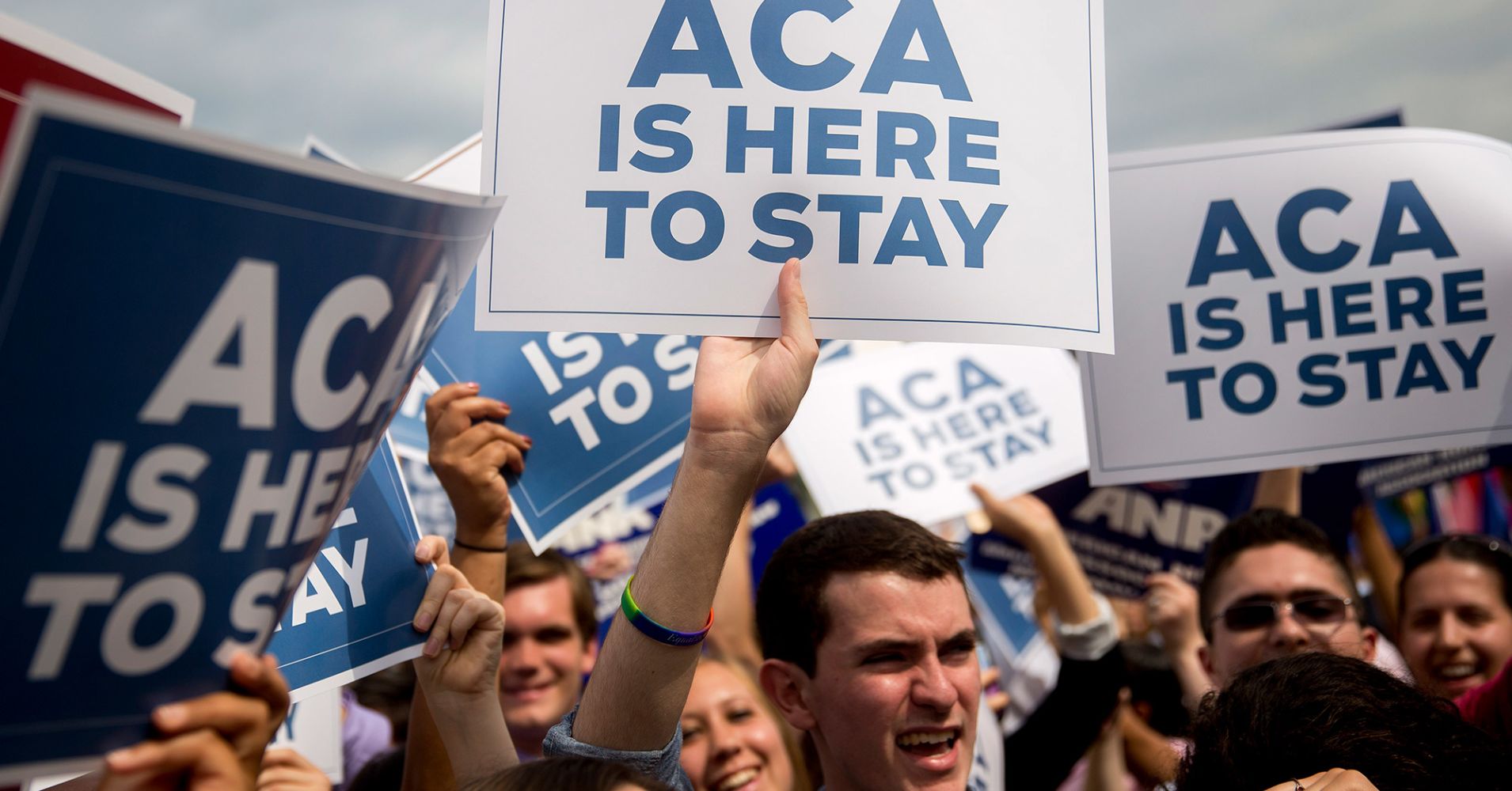 Demonstrators in support of U.S. President Barack Obama's health-care law, the Affordable Care Act (ACA), hold up 'ACA is Here to Stay' signs after the U.S. Supreme Court ruled 6-3 to save Obamacare tax subsidies outside the Supreme Court in Washington, D.C. June 25, 2015.